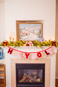 Handmade HOLLY JOLLY Christmas fabric banner featuring pink and red velvet and sequin letters with white scalloped edges, hanging from a red ribbon.